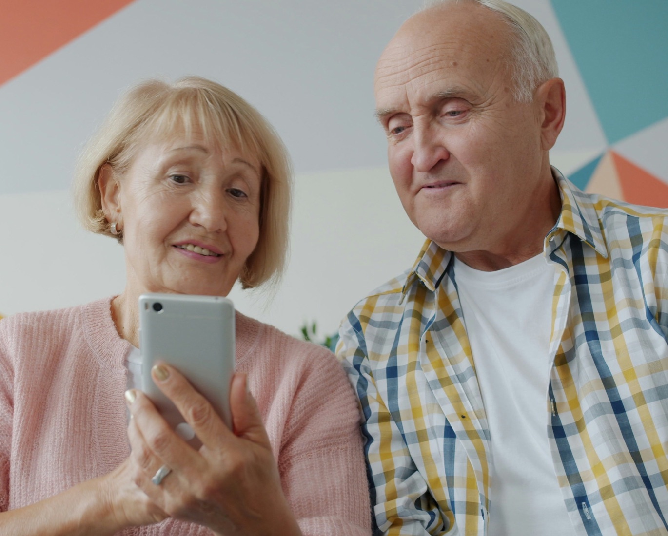 A smiling senior couple looking at a smartphone together